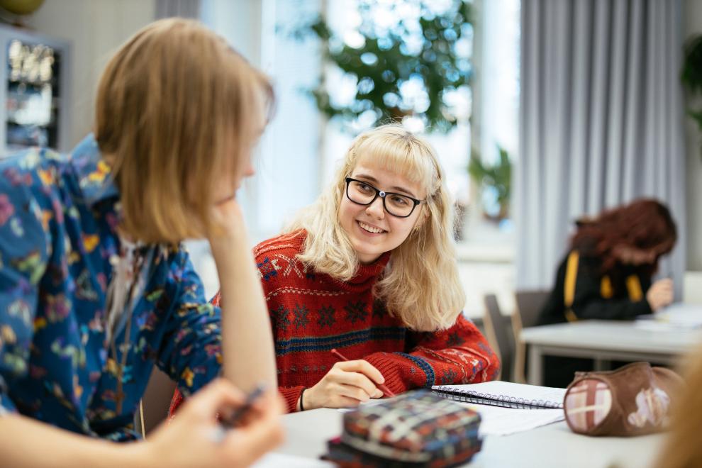 Kaksi nuorta opiskelee pöydän ääressä luokkahuoneessa.