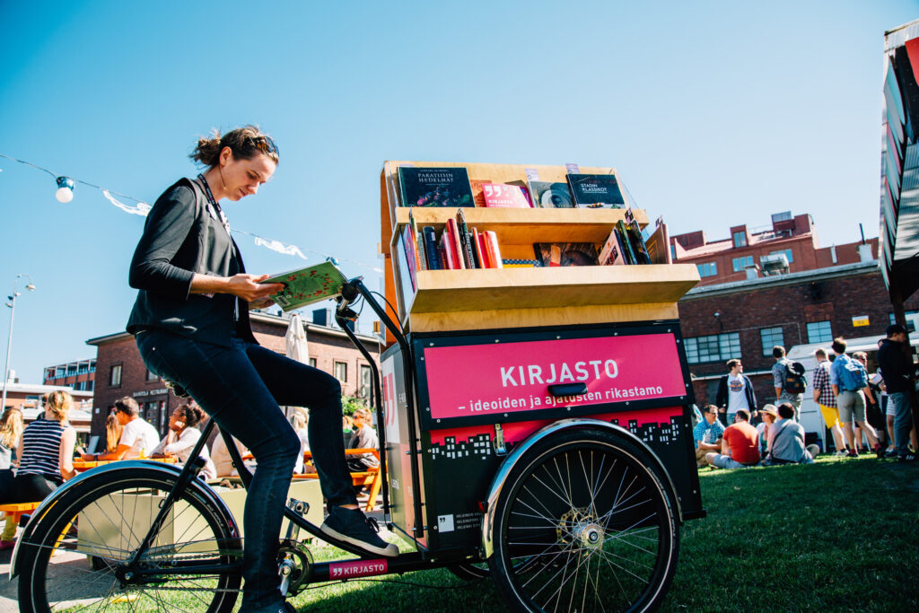 Henkilö lukee kirjaa kirjastopyörässä.