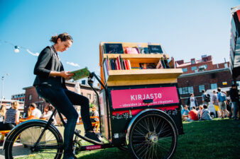 Henkilö lukee kirjaa kirjastopyörässä.