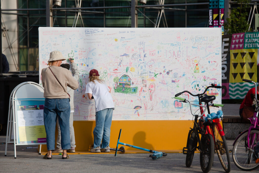 Kaksi henkilöä osallistuvat katutaideteoksen tekoon.